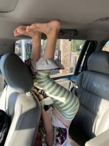 child in car with feet on roof