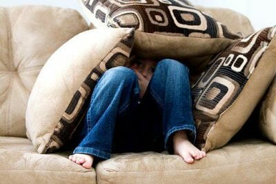 child hiding in cushions